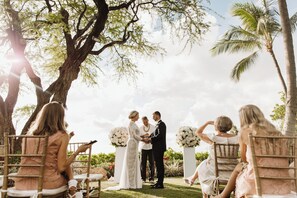 A wedding ceremony outdoors with guests seated on chairs.