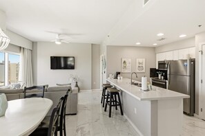 A modern kitchen with a central island, stainless steel appliances, and a dining area with a white table and chairs.