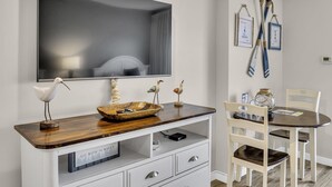 Una habitación moderna con un espejo grande, un aparador de madera, sillas blancas y una mesa de comedor.