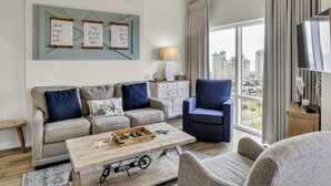 Una sala de estar con sofá, sillón, mesa de centro y vistas de la ciudad.