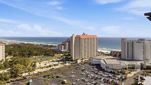 Un hôtel doté d’un parking, offrant une vue sur la plage et comprenant un grand bâtiment avec un toit rouge.