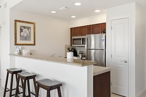 A kitchen with a central island, wooden cabinets, stainless steel appliances, and a framed picture on the wall.
