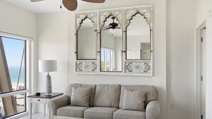 Un salon avec un canapé beige, une table basse en bois et un grand miroir décoratif.