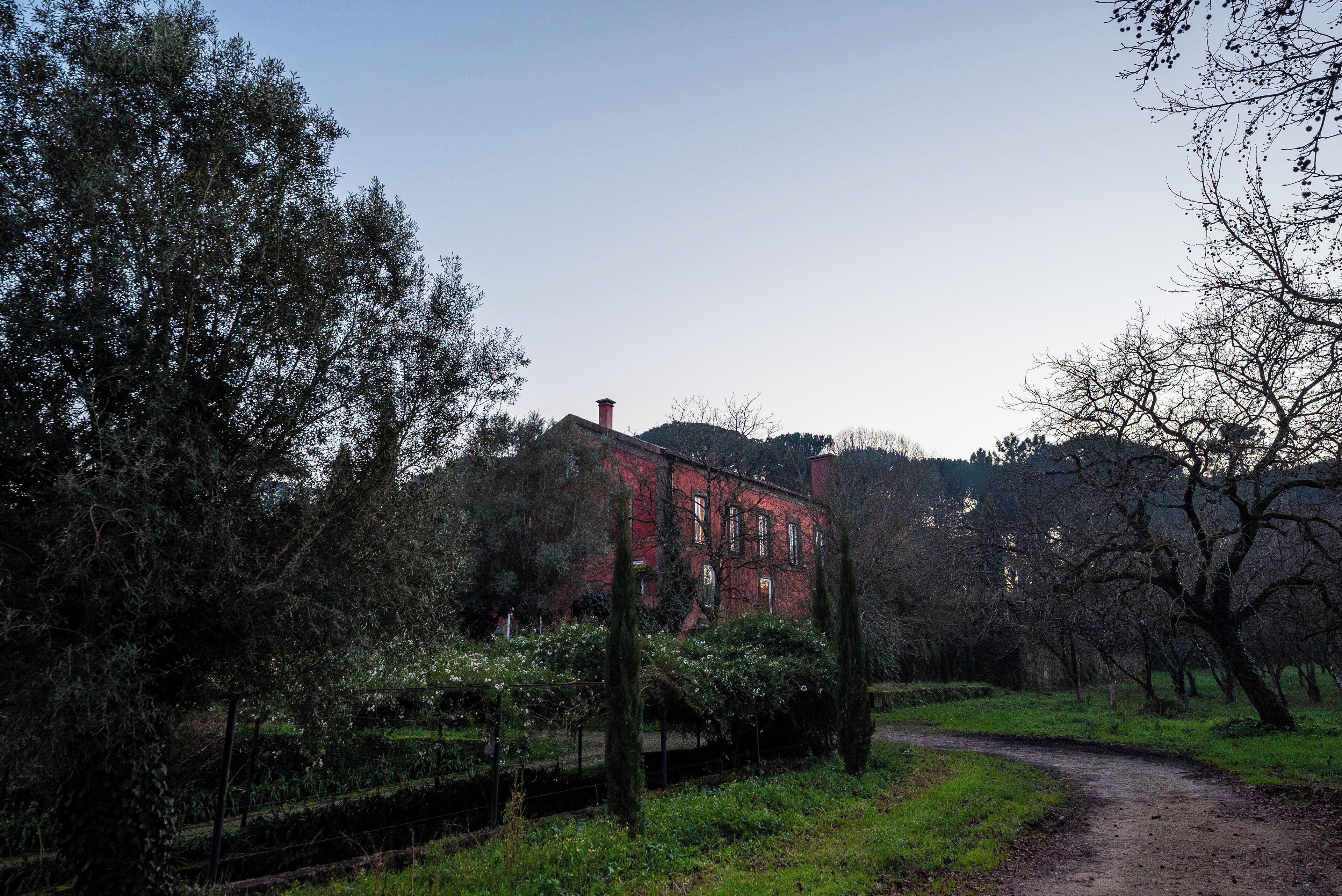 A red brick building surrounded by trees and a path.
