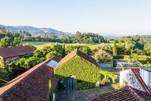 A vineyard with buildings surrounded by lush greenery and hills in the background. - Quinta do Ameal (Ponte de Lima)