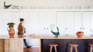 A kitchen with a wooden countertop, white cabinets, decorative peacock figurines, and a bowl of fruit. - Quinta do Ameal (Ponte de Lima)