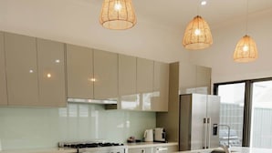 Een moderne keuken met een centraal eiland, barstoelen en hanglampen.