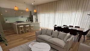 Een moderne woonkamer met een bank, een salontafel en een eethoek met een tafel en stoelen.