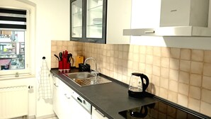A modern kitchen with white cabinets, a black countertop, a sink, and a kettle.