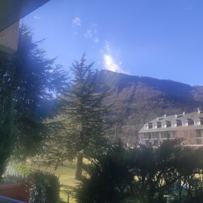 Un edificio con un tejado simétrico y varias ventanas, rodeado de árboles y una montaña al fondo.