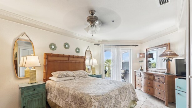 A bedroom with a bed, nightstands, a dresser, a mirror, and a ceiling fan. - Ocean Gate I Garden View Retreat (St. Augustine)