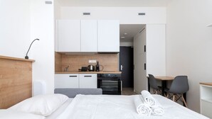 Une chambre d’hôtel comprenant un lit, un bureau, une chaise, une kitchenette et une salle de bain.