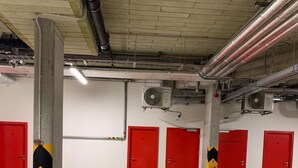 Un parking avec des piliers en béton, des portes rouges et des murs blancs.