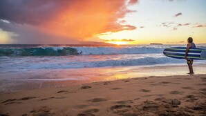 Une scène de plage avec des vagues et un coucher de soleil.
