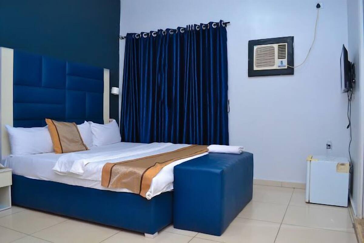 Ein Hotelzimmer mit einem großen Bett, einem Nachttisch, einem Fernseher und einem kleinen weißen Schrank.