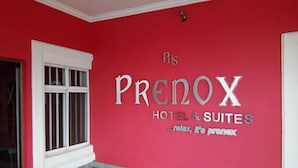 A red wall with the text "PRESNOX HOTEL & SUITES" and a window with bars. - Prenox Hotel and Suites  (Benin City)