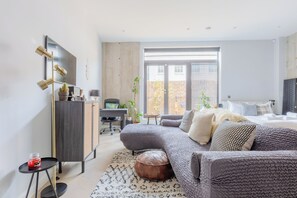 A modern living room with a sofa, a desk, and a bed. - Stylish Studio in Hackney with Private Terrace (Greater London)