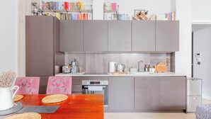 A modern kitchen with grey cabinets, a wooden dining table, and a coffee machine. - Stylish Studio in Hackney with Private Terrace (Greater London)