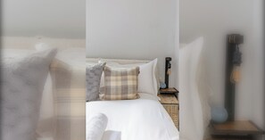 A bedroom with a bed, pillows, a nightstand, and a wall-mounted lamp. - Stylish Studio in Hackney with Private Terrace (Greater London)