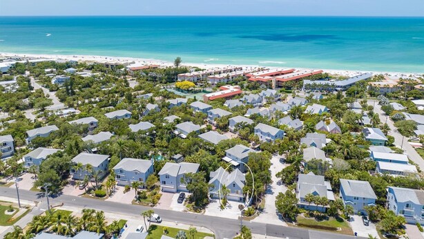 An aerial view of a coastal residential area with houses, a beach, and a clear blue sky. - AMI's Salty Breeze: 5-min walk to Beach, community pool, relaxing decor (Holmes Beach)
