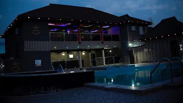 A large building with a swimming pool, balconies, and string lights. - Lawsons Residence and Suites (Uhiere)