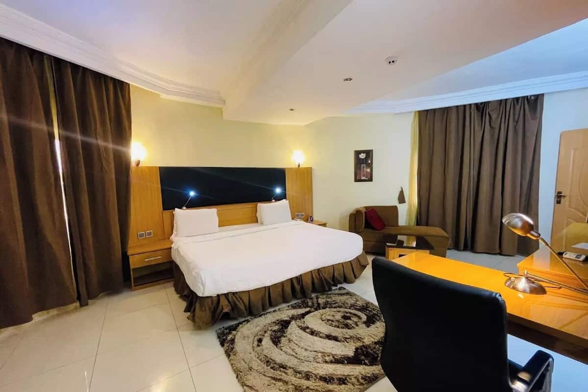 Una habitación de hotel con una cama grande, un escritorio con silla, un sofá y un televisor.