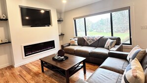 Una sala de estar moderna con chimenea, un sofá grande, una mesa de centro y un ventilador de techo.