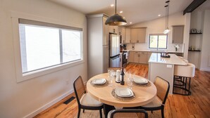 Una cocina moderna con armarios blancos, una isla central y una zona de comedor con una mesa redonda y sillas.