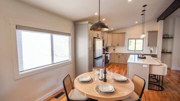 A modern kitchen with white cabinets, a central island, and a dining area with a round table and chairs.