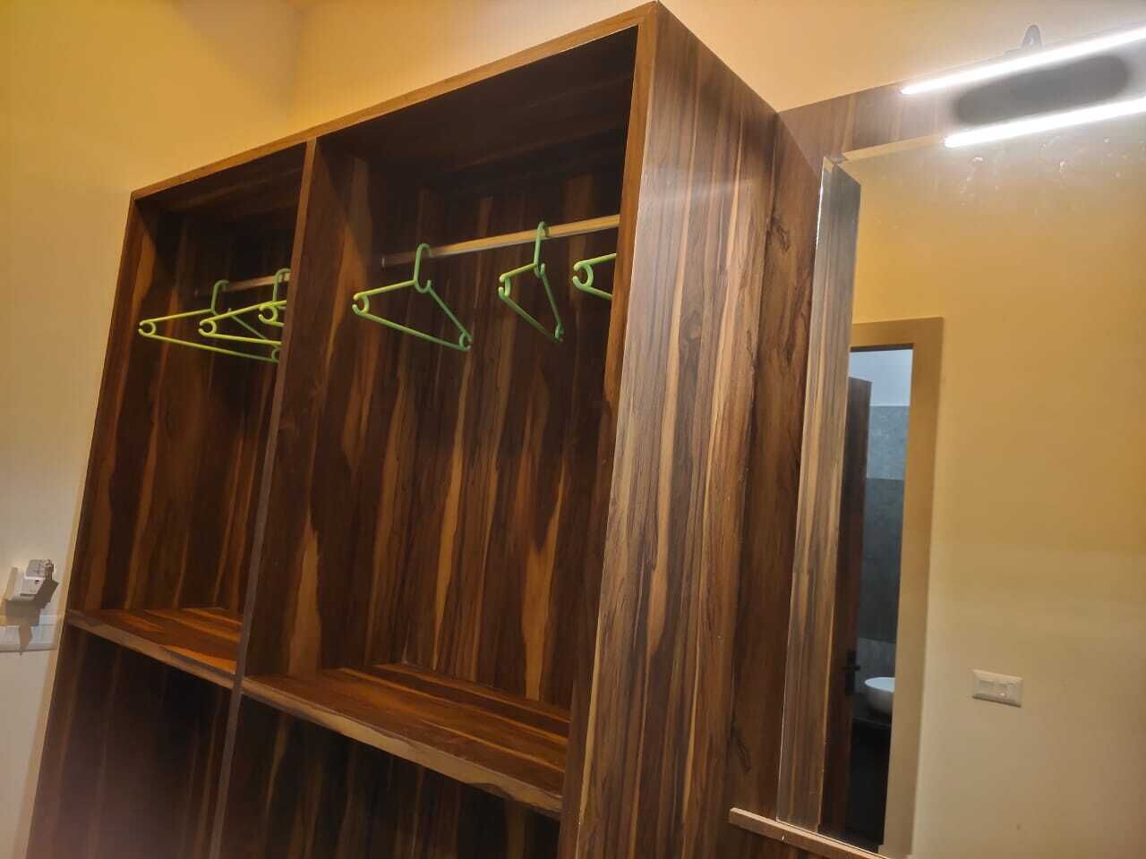 A wooden wardrobe with multiple compartments and a hanging rod.
