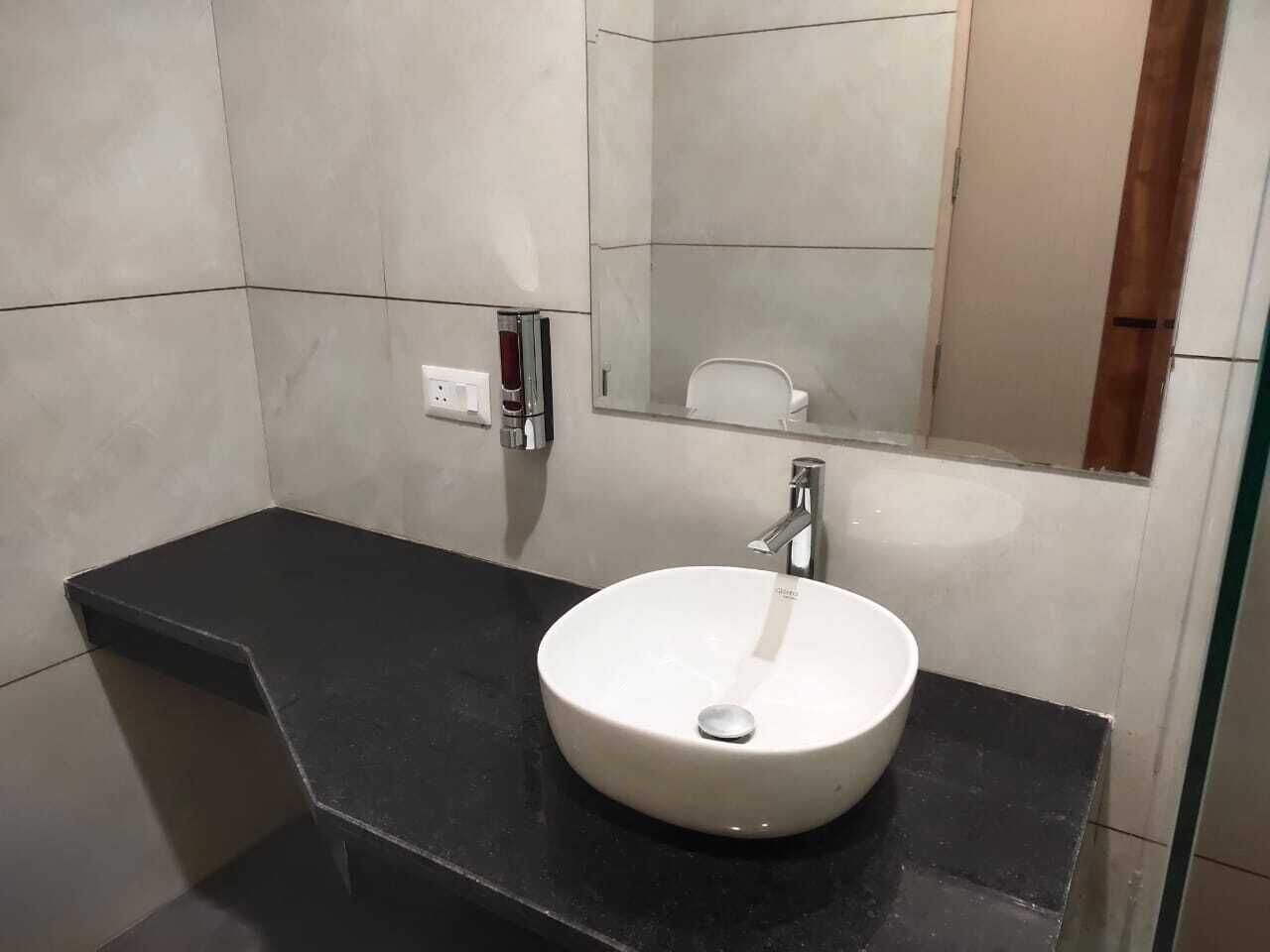A modern bathroom with a black countertop, a white sink, and a mirror above it.