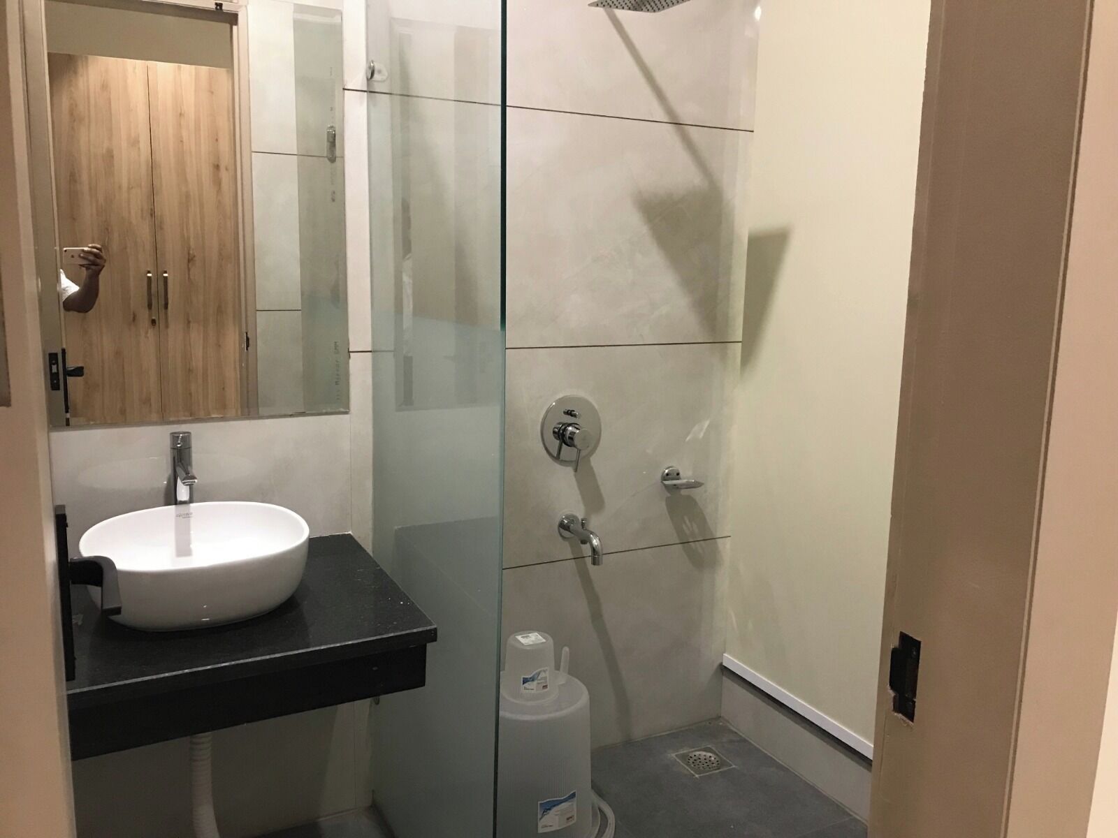 Un baño moderno con lavamanos blanco, cabina de ducha de vidrio y mueble de madera.