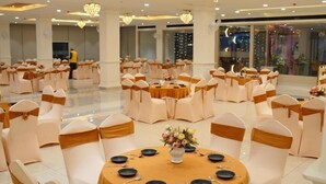 A banquet hall with round tables, chairs, chandeliers, and a ceiling fan. - AJ's Arcade (Pathankot)