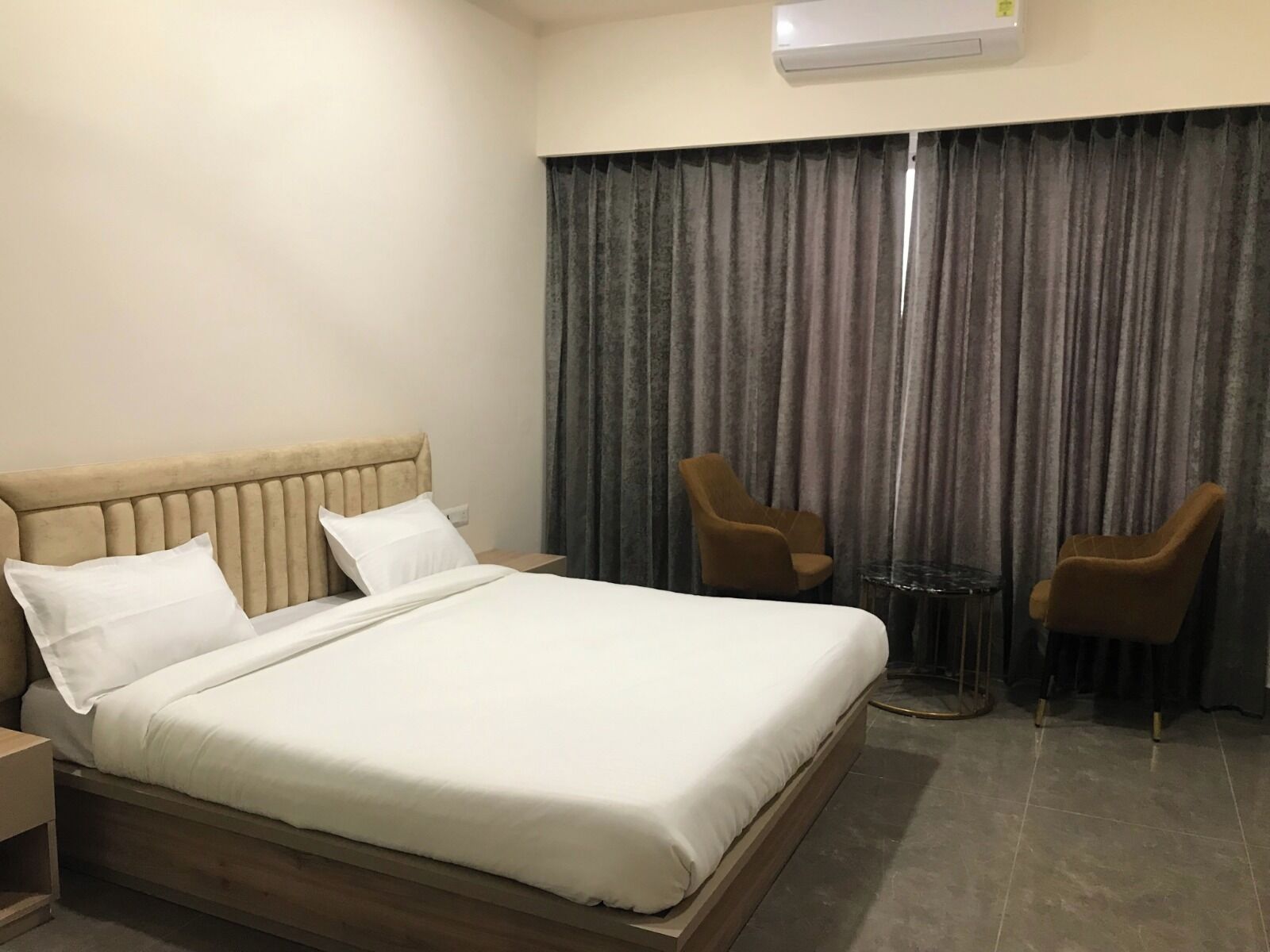 Habitación de hotel con una cama grande, dos sillones, una mesita y un telón de fondo.