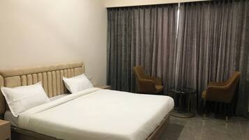 Habitación de hotel con una cama grande, dos sillones, una mesita y un telón de fondo.
