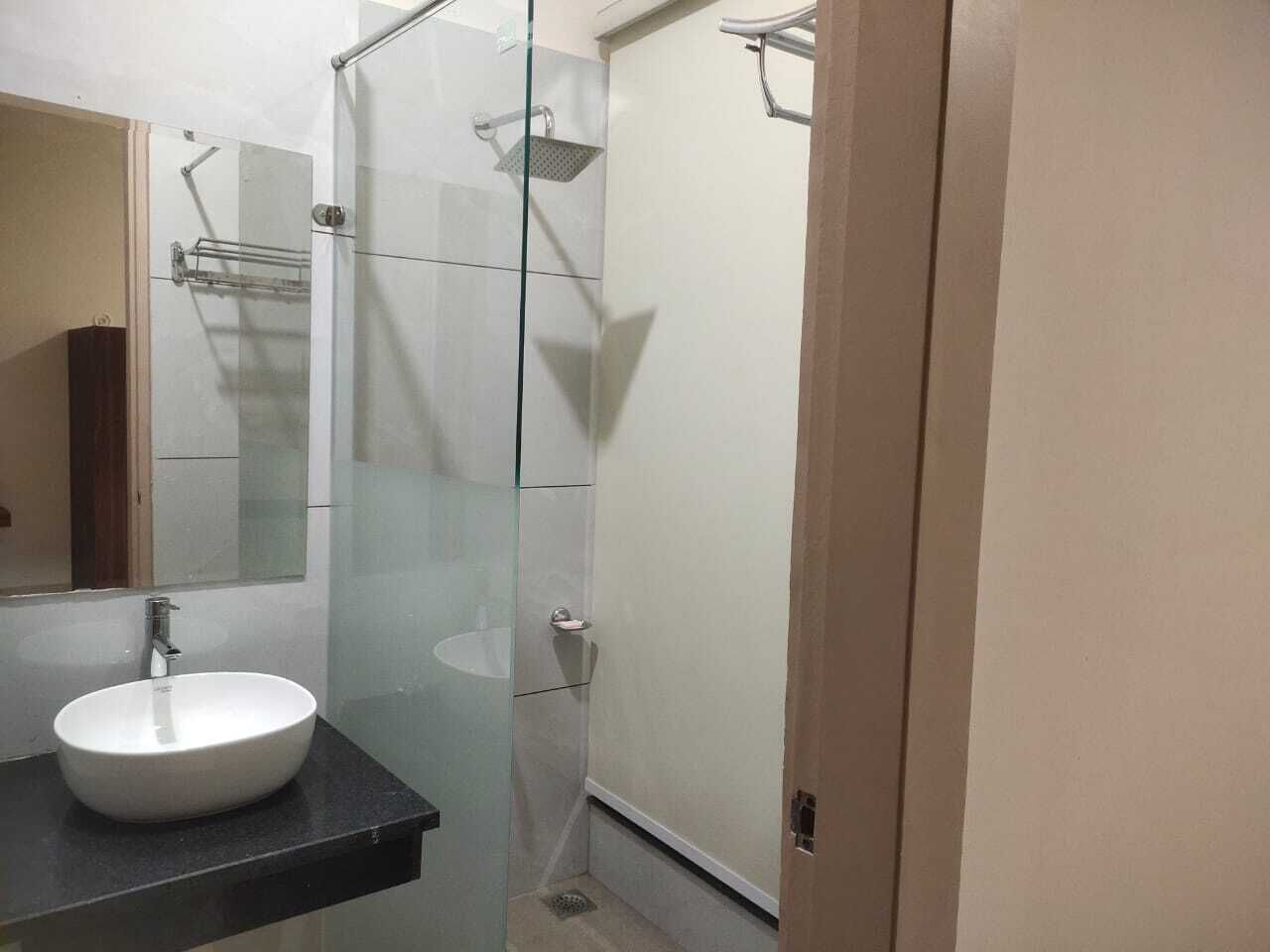 A bathroom with a glass-enclosed shower, a white sink, and a mirror.