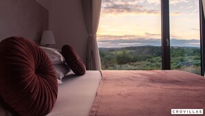 Une chambre à coucher avec un grand lit, une vue sur la campagne et une fenêtre avec des rideaux.