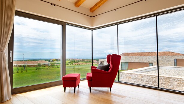 A spacious room with large windows, a red chair, and a small ottoman. - Villa Sanpadeo Nearby Novigrad - Crovillas (Brtonigla)