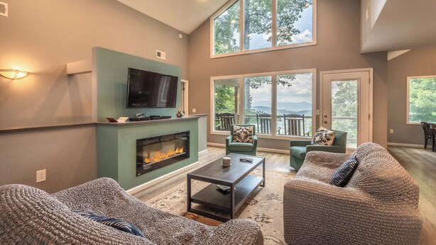 Ein geräumiges Wohnzimmer mit Kamin, bequemer Sitzgelegenheit und großen Fenstern mit Blick ins Freie.