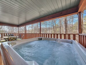 A hot tub on a wooden deck with a view of leafless trees.