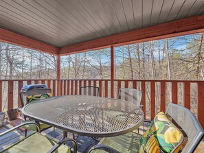 A covered outdoor patio with a round metal table and chairs, surrounded by a wooden railing.