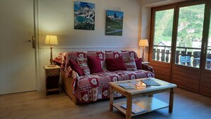 A cozy room with a patterned sofa, a small wooden table, and two lamps. - Resort center, 3rd floor, balcony, parking, 53m², Valloire (Valloire)