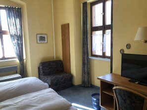 A hotel room with two beds, a desk with a TV, a chair, a window with curtains, a door, and a picture on the wall. - Gasthaus Klosterhof (Wertheim)