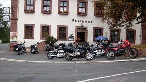 Un edifici amb un rètol que diu "Gasthaus" i diverses motocicletes aparcades al davant.
