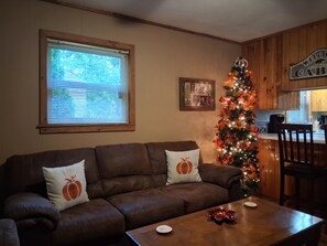 Una sala acogedora con un sofá de cuero marrón, una mesa de centro de madera y un árbol de Navidad.
