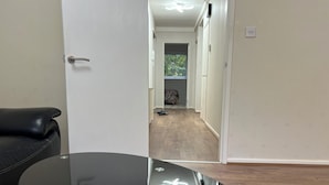 Une pièce avec un canapé en cuir noir, une table à plateau en verre et un plancher en bois.