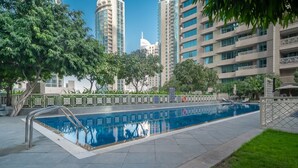 A swimming pool with a metal ladder, surrounded by a low fence and trees. - Bellavista-29BLVD Fabulous Fountain View (Dubai)