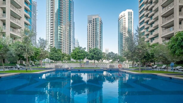 A swimming pool surrounded by high-rise buildings, trees, and sun loungers. - Bellavista-29BLVD Fabulous Fountain View (Dubai)