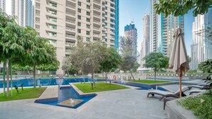 A modern outdoor pool area with a fountain, surrounded by greenery and tall buildings in the background. - Bellavista-29BLVD Fabulous Fountain View (Dubai)