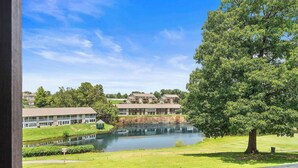 A view of a building with a pond in front, surrounded by greenery and a clear sky. - Pointe Royale Getaway – ‘Fore’ 4 (Branson)